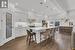 Kitchen with decorative light fixtures, stainless steel appliances, a kitchen island, white cabinetry, and a kitchen breakfast bar