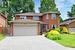 Traditional home with brick siding, a front yard, fence, a garage, and driveway