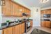 Kitchen with tasteful backsplash, extractor fan, stainless steel range with electric stovetop, and black microwave