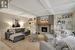 Living room featuring crown molding, a brick fireplace, built in shelves, beamed ceiling, and light parquet flooring