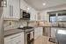 Kitchen with appliances with stainless steel finishes, tasteful backsplash, sink, light parquet flooring, and white cabinetry