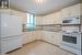 Kitchen with white appliances, light stone countertops, sink, and white cabinets