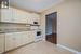 Kitchen featuring a textured ceiling, light stone counters, white cabinets, and white appliances