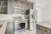 Kitchen with dark brown cabinetry, light tile patterned floors, stainless steel appliances, light stone countertops, and decorative backsplash