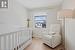 Bedroom with light wood finished floors, a crib, visible vents, and baseboards