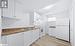 Kitchen with white appliances, sink, light hardwood / wood-style floors, and white cabinets