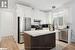 Kitchen with white cabinets, stainless steel appliances, a kitchen island, and light hardwood / wood-style floors