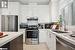 Kitchen featuring ventilation hood, white cabinets, light stone countertops, and appliances with stainless steel finishes