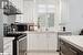 Kitchen featuring white cabinetry, sink, range hood, stainless steel range with electric stovetop, and light tile patterned floors