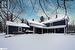 Snow covered back of property with a hot tub