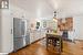 Kitchen with sink, white cabinetry, hanging light fixtures, stainless steel appliances, and wall chimney range hood