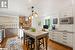 Kitchen featuring wall chimney exhaust hood, a breakfast bar, stainless steel microwave, pendant lighting, and white cabinets