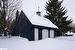 View of snow covered exterior featuring a garage and an outdoor structure