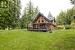 Back of property featuring a deck and a yard overlooking west coast forest