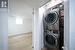 Washroom with stacked washing maching and dryer and light hardwood / wood-style floors