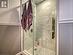 Glass shower doors & gleaming tile in shower of upper level apartment