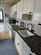 Kitchen with tasteful backsplash, white cabinetry, extractor fan, sink, and light hardwood / wood-style flooring