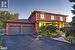 Twilight view of front facade with a double garage, parkign for 6 in driveway, covered porch and perennial gardens