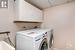 Laundry room with front load washer and dryer, cabinets, and utility sink.