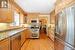 Kitchen featuring light wood-type flooring, appliances with stainless steel finishes, crown molding, and light stone countertops