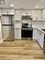 Kitchen featuring tasteful backsplash, white cabinetry, stainless steel appliances, and light wood-type flooring