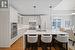 Kitchen featuring sink, appliances with stainless steel finishes, white cabinetry, an island with sink, and decorative light fixtures