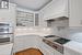 Kitchen featuring decorative backsplash, appliances with stainless steel finishes, custom range hood, and white cabinets