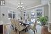 Dining area featuring dark wood-type flooring, ornate columns, a tray ceiling, and a notable chandelier