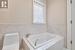 Bathroom featuring tiled tub and toilet