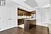 Kitchen with a kitchen island with sink, decorative backsplash, dark hardwood / wood-style flooring, and stainless steel appliances