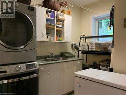Modern fully finished laundry room with plenty of storage and double sinks. - 