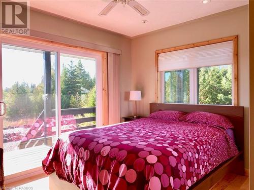 This sunny 2nd bedroom also enjoys a lovely water view & patio door to covered decking. - 34 Hatt Street, Northern Bruce Peninsula, ON - Indoor Photo Showing Bedroom