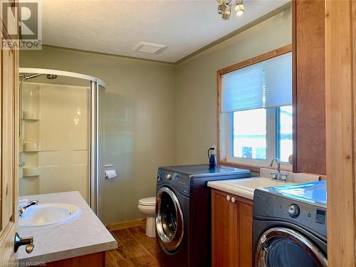 Oversized main bathroom has a shower and laundry area with high quality front-loading washer/dryer, laundry basin, and built-in storage cabinetry above & below. - 34 Hatt Street, Northern Bruce Peninsula, ON - Indoor Photo Showing Laundry Room