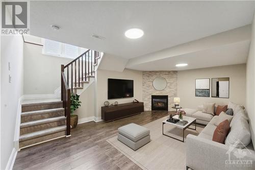 Lovely finished basement with laminate flooring and gas burning stone face fireplace (virtually staged) - 109 Hawkeswood Drive, Ottawa, ON - Indoor With Fireplace