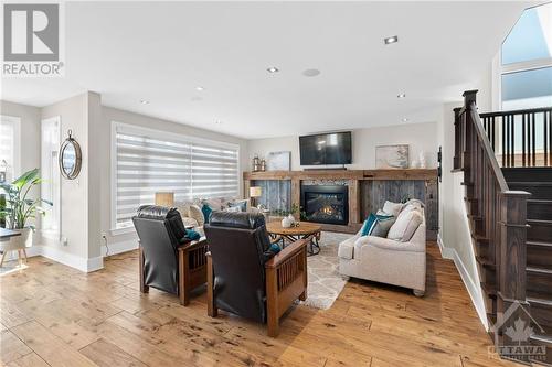Cozy fireplace beckons, inviting you to snuggle up with a good book and unwind in comfort. Continuing up the gorgeous staircase, you're greeted by large oversized windows that continue to bathe th - 52 Moore Street, Ottawa, ON - Indoor With Fireplace