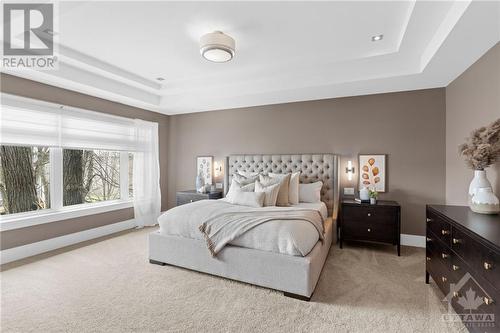 Expansive primary bedroom, classy coffered ceilings add sophistication, while large windows flood the space with light. Wall-to-wall carpeting offers comfort, complementing the ensuite and walk-i - 52 Moore Street, Ottawa, ON - Indoor Photo Showing Bedroom