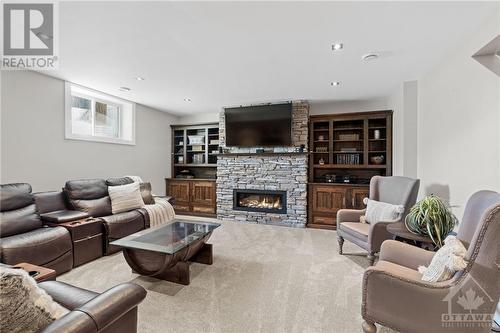 Lower level family room boasts plush carpeting, a stunning fireplace, and built-in shelving, creating a cozy and inviting atmosphere perfect for relaxation and gatherings. - 52 Moore Street, Ottawa, ON - Indoor Photo Showing Living Room With Fireplace