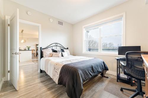 Primary bedroom has large window with custom blinds providing a scenic view of nature beyond. - 67 Haddington Street|Unit #304, Caledonia, ON - Indoor Photo Showing Bedroom