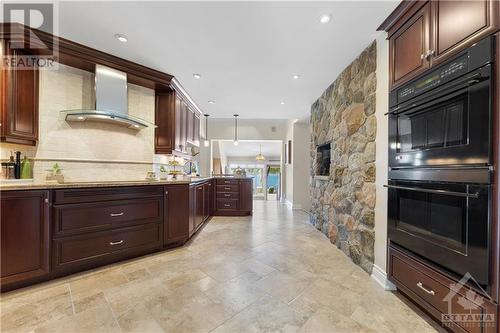 Go up a step from the foyer and enter this gorgeous chef kitchen with double oven, paneled fridge and dishwasher to make this high end kitchen something dreams are made off.  Rock wall is the back - 3756 Mapleshore Drive, Kemptville, ON - Indoor Photo Showing Kitchen