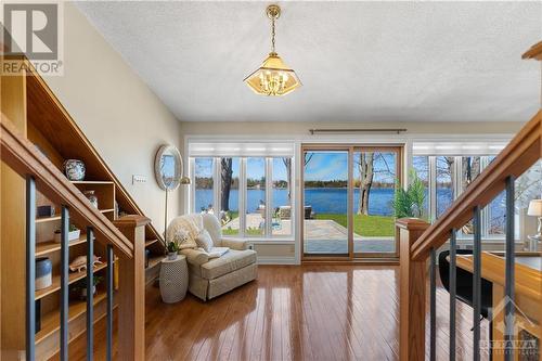 This stunning sunroom / entertainment space has wall to wall windows overlooking the river.  This is sunken from the kitchen.  Beautiful hardwood floors and artistic built in shelving unit are on - 3756 Mapleshore Drive, Kemptville, ON - Indoor Photo Showing Other Room