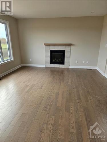 very nice hardwood is actually lighter than photo shows...great combo of colours and finishes chosen by builder designers - 828 Snowdrop Crescent, Ottawa, ON - Indoor Photo Showing Living Room With Fireplace