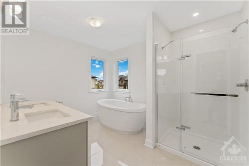 Ensuite with double sink vanity, quartz counters and stand alone tub. Upgraded ceramic tiles - 723 Odyssey Way, Ottawa, ON - Indoor Photo Showing Bathroom