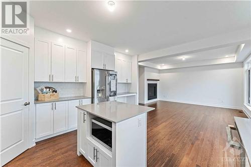 Bright white kitchen with centre island, quartz counters and a walk in pantry - 705 Rosales Ridge, Ottawa, ON - Indoor Photo Showing Kitchen With Upgraded Kitchen