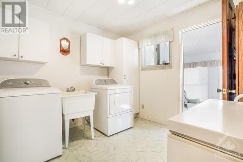 Handy and good size mud room with laundry tub, cupboards beside & above washer/dryer and access to the sunroom. - 927-931 Laurier Street, Rockland, ON - Indoor Photo Showing Laundry Room