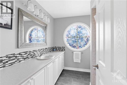 Beautiful second level family bathroom complete with a Rose Window and stained design for privacy. Tiled floors and large vanity and mirror. - 2181 Des Grands Champs Way, Ottawa, ON - Indoor Photo Showing Bathroom