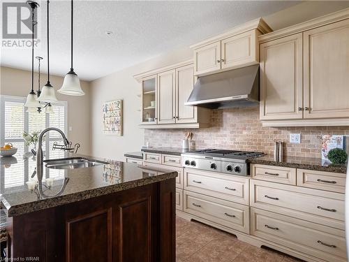 The high-end creme kitchen features sleek granite counters, furniture base cabinetry with all drawers on lower portion, crown molding, open decorative shelving, loads of storage, tumbled marble backsp - 110 Golf Course Road, Woolwich, ON - Indoor Photo Showing Kitchen With Double Sink With Upgraded Kitchen