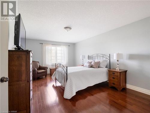 Situated at the back of the house, this handsome primary suite offers a double door entry, hickory hardwood flooring, a spacious walk in closet and views of the golf course. - 110 Golf Course Road, Woolwich, ON - Indoor Photo Showing Bedroom