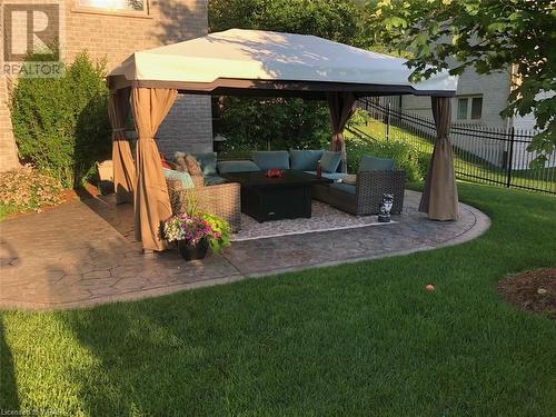 The curved stamped concrete patio boasts a metal gazebo with privacy screens (included). - 110 Golf Course Road, Woolwich, ON - Outdoor With Deck Patio Veranda