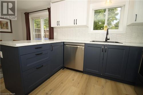 Updated eat-in L-shaped countertop kitchen with matching black sink and gooseneck tap, dark navy lower and white upper cabinets, white polygon tiled backsplash, ceiling lights, walk-out to deck, inclu - 136 Oprington Court, Kitchener, ON - Indoor Photo Showing Kitchen With Upgraded Kitchen