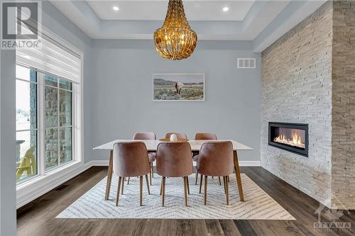 Host a dinner party in the stunning dining room that features an accent stone wall and benefits from the double-sided fireplace - 153 Barrdon Road, Ottawa, ON - Indoor Photo Showing Dining Room With Fireplace
